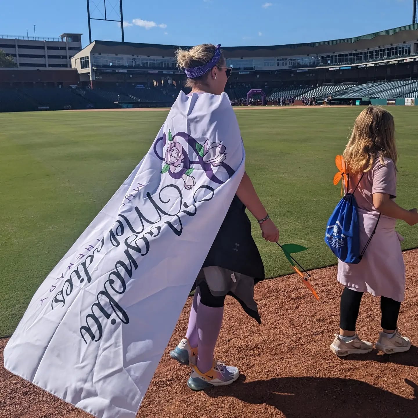 Team member wearing a Magnolia Melodies flag as a cape on the field