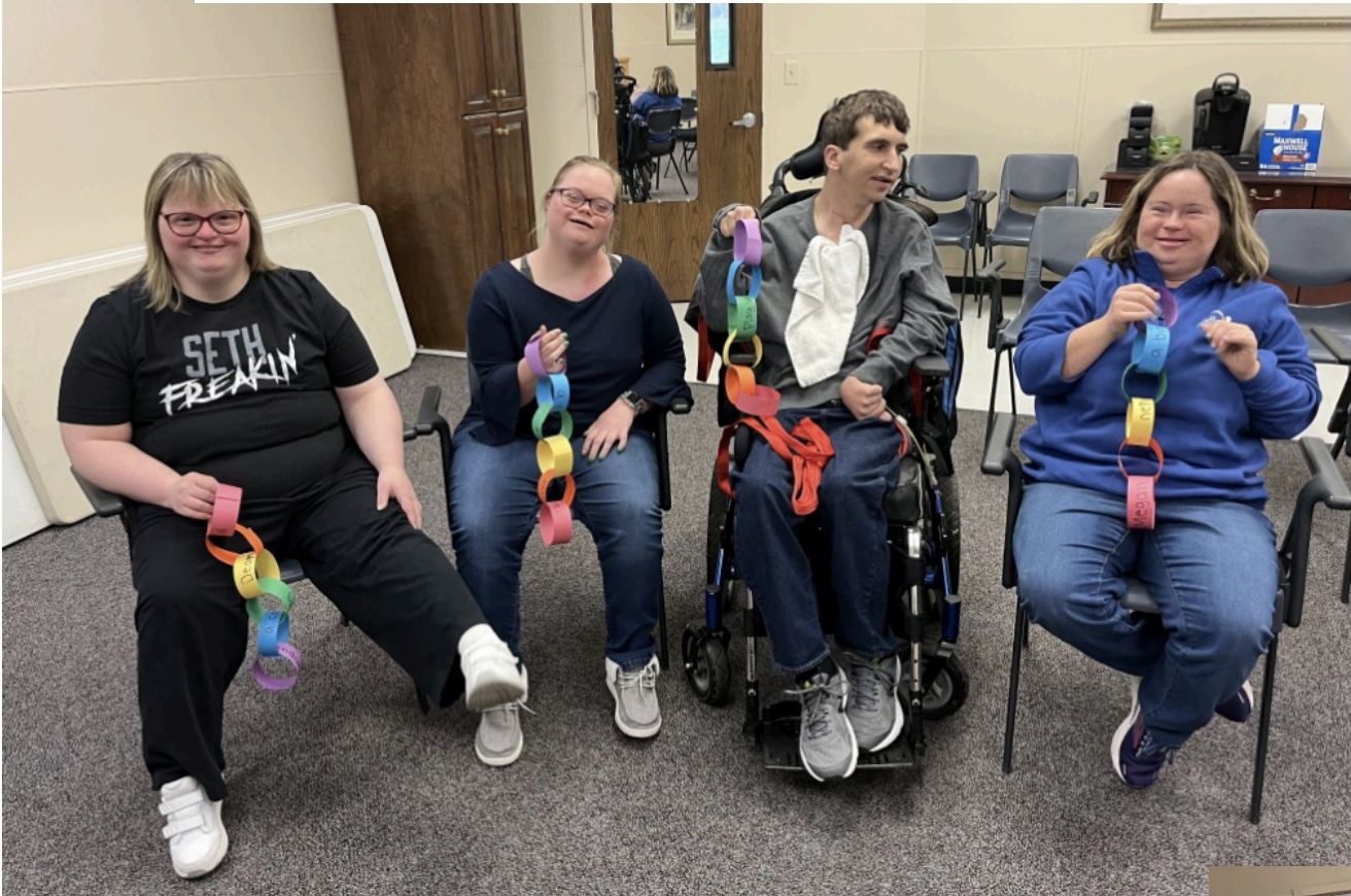 Connections group members smiling and holding a colorful paper chain