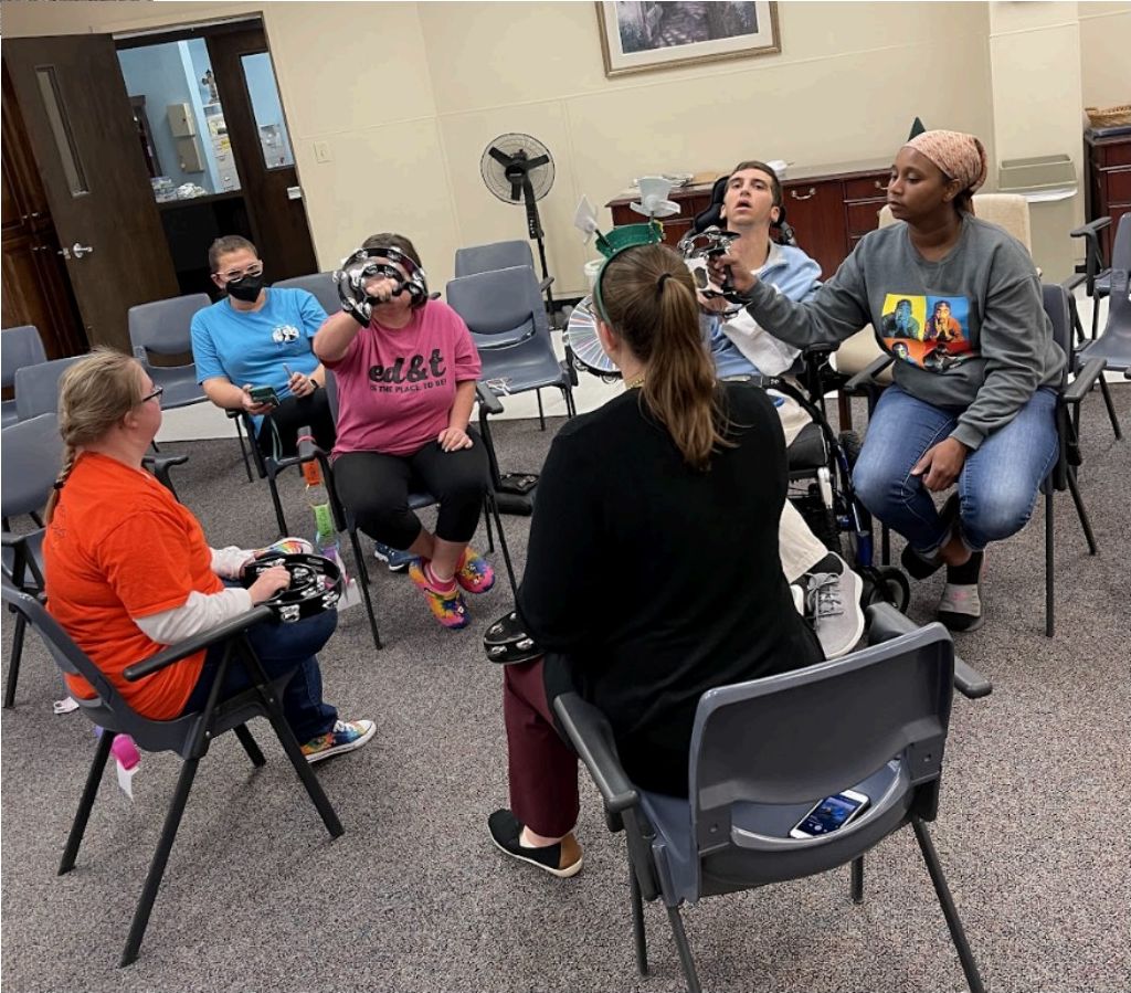Connections group sitting in a circle playing tambourines and percussion instruments
