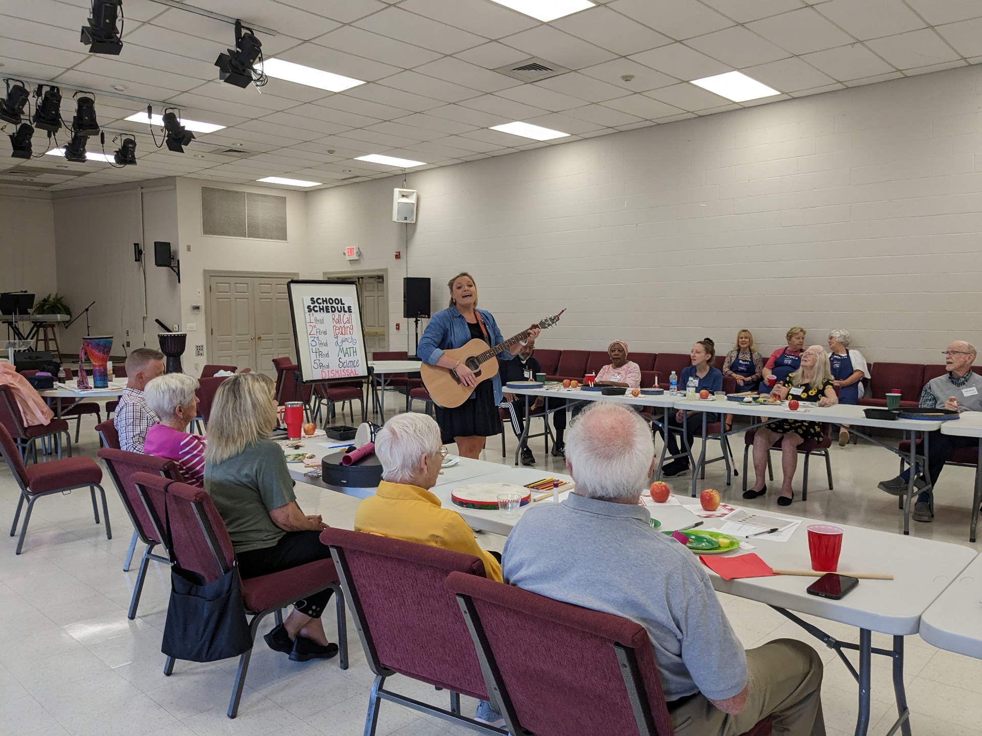 Randi leading a school-themed sing-along with a circle of older adults