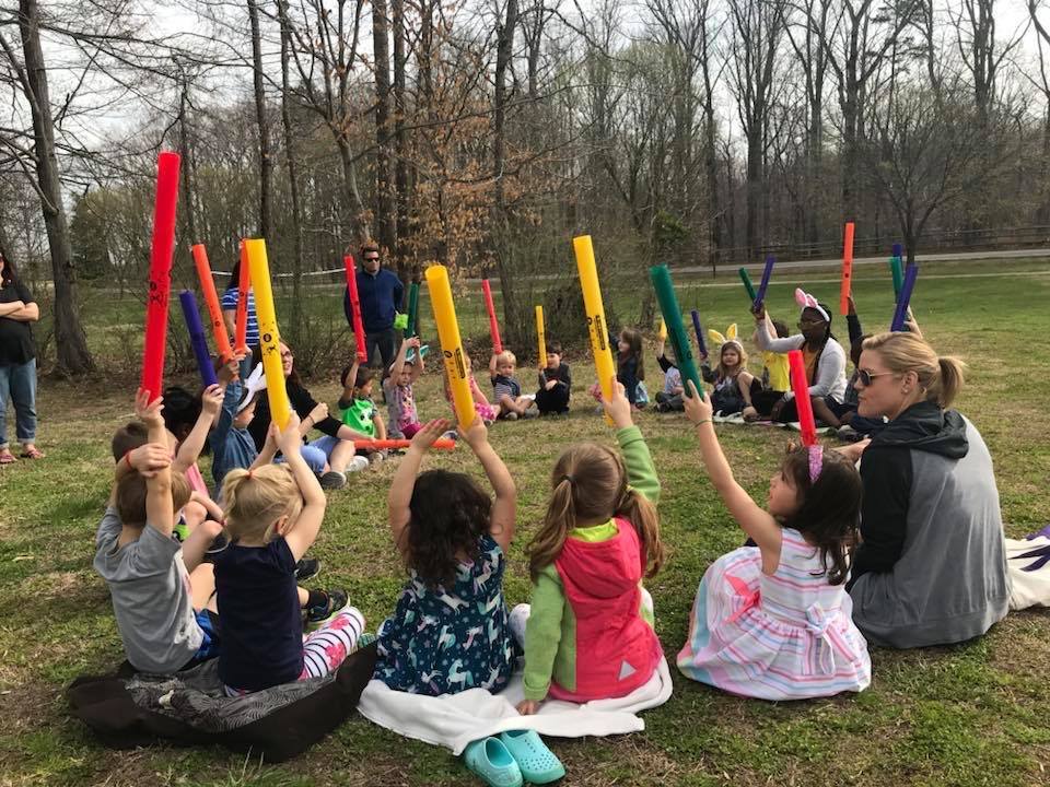 Group outdoors holding colorful boomwhackers in the air