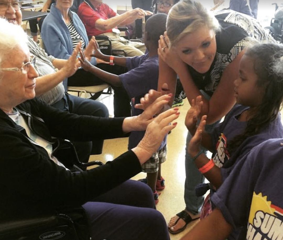 Children and seniors sharing high-fives in an intergenerational session