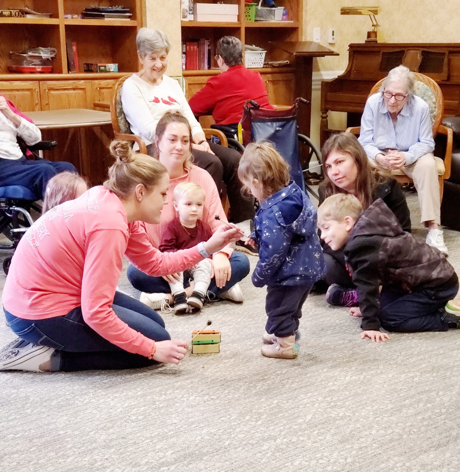 Young children and seniors gathered around a small xylophone